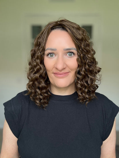 Woman with curly hair topper wearing a black shirt against a neutral background